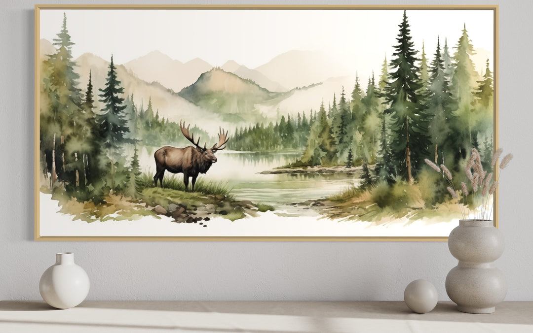 Moose in wilderness watercolor framed canvas wall art above a shelf with decorative vases.