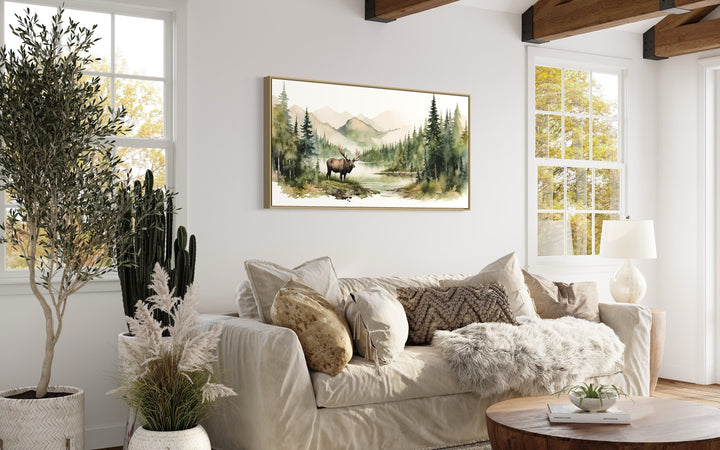 Framed canvas wall art featuring a watercolor moose in a serene mountain and forest landscape.