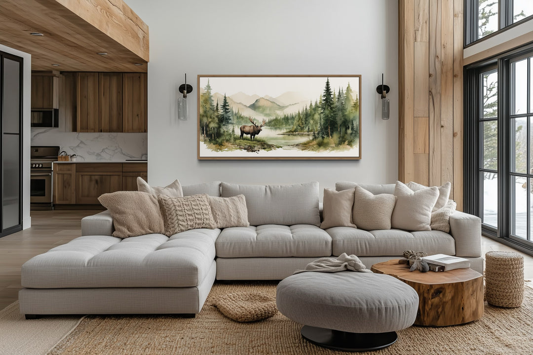 Moose in wilderness watercolor framed canvas wall art above a sofa in a rustic living room.