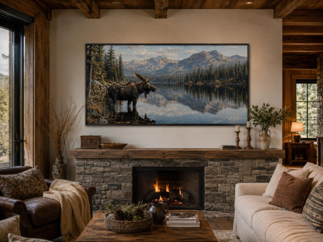 Moose near lake canvas wall art displayed above a stone fireplace mantel in a rustic cabin.