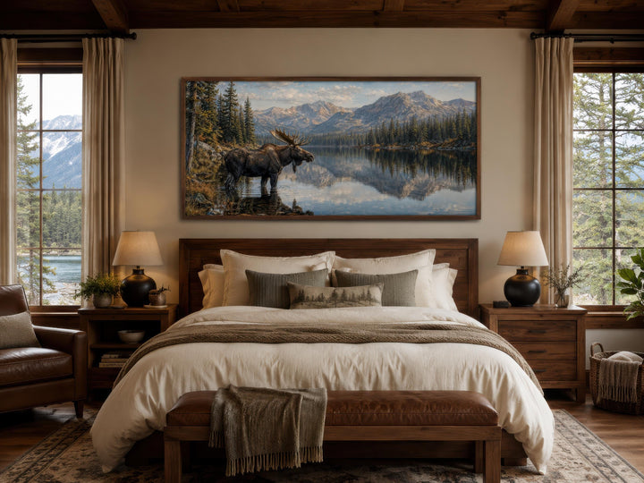 Moose Near Lake wall art canvas print hanging above a bed in a rustic cabin bedroom.