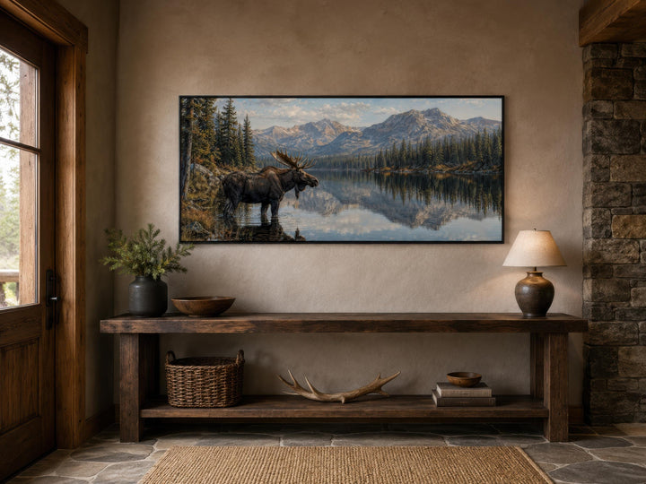 Moose near a mountain lake canvas wall art displayed above a rustic wooden console table.