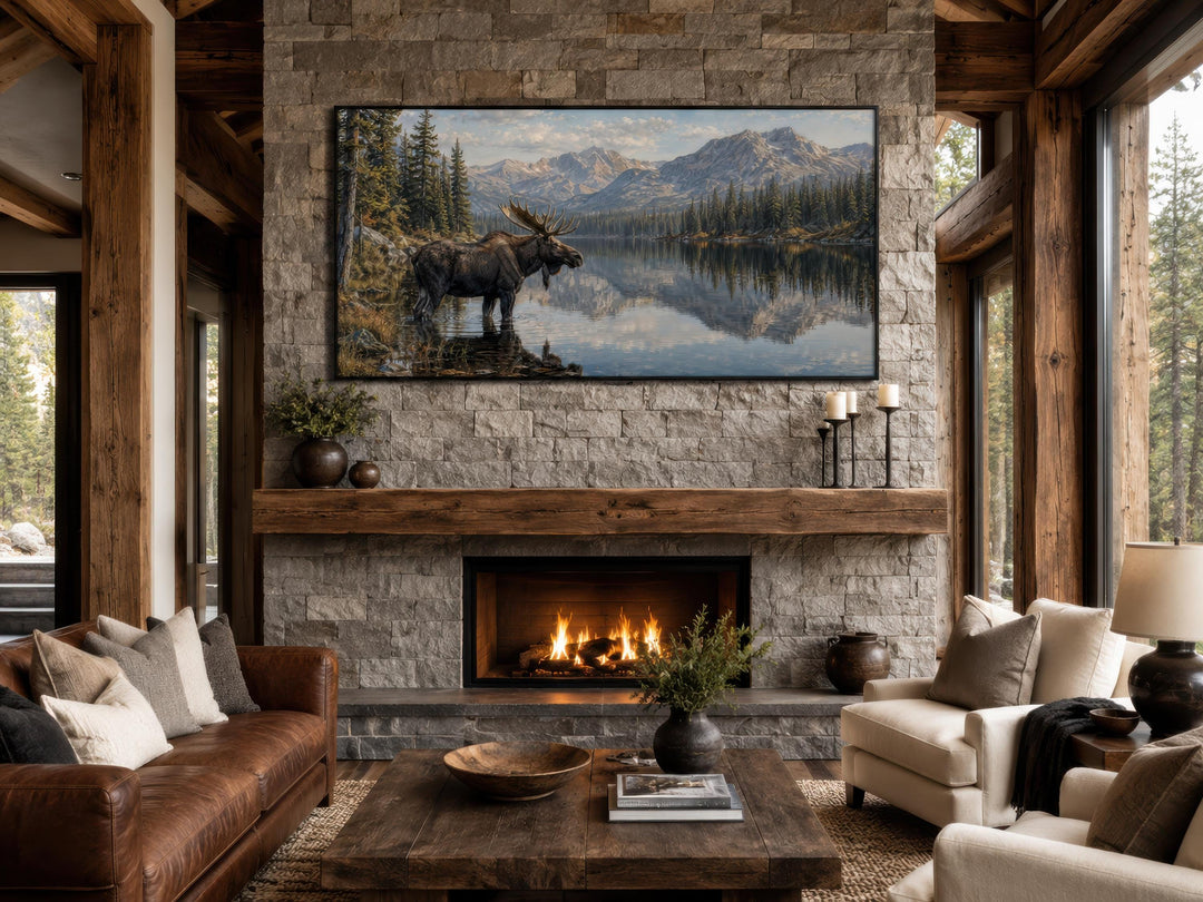 Moose Near Lake wall art canvas print displayed above a stone fireplace mantel in a rustic room.