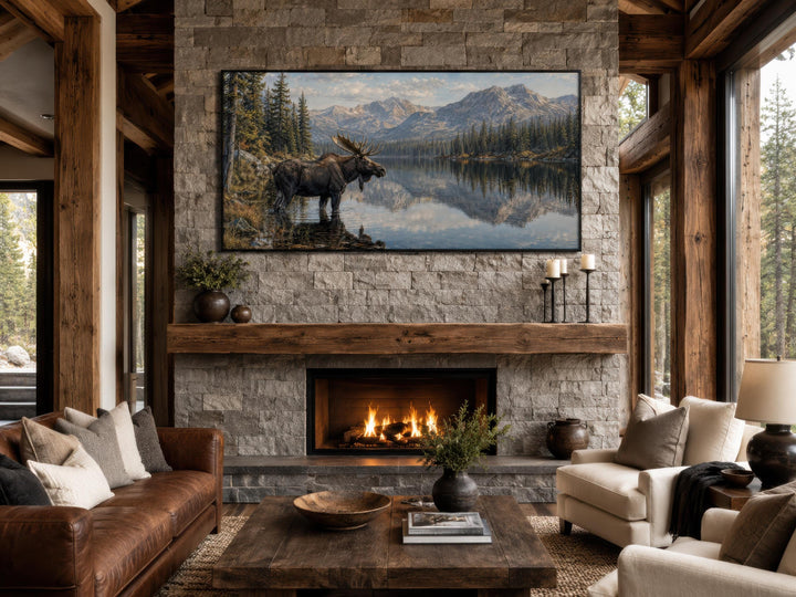 Moose Near Lake wall art canvas print displayed above a stone fireplace mantel in a rustic room.