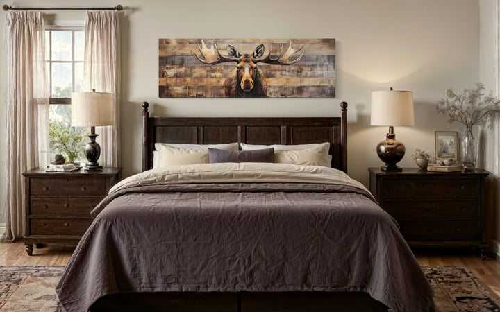 Moose painted on wood rustic horizontal framed canvas wall art hanging above a bed in a cabin.