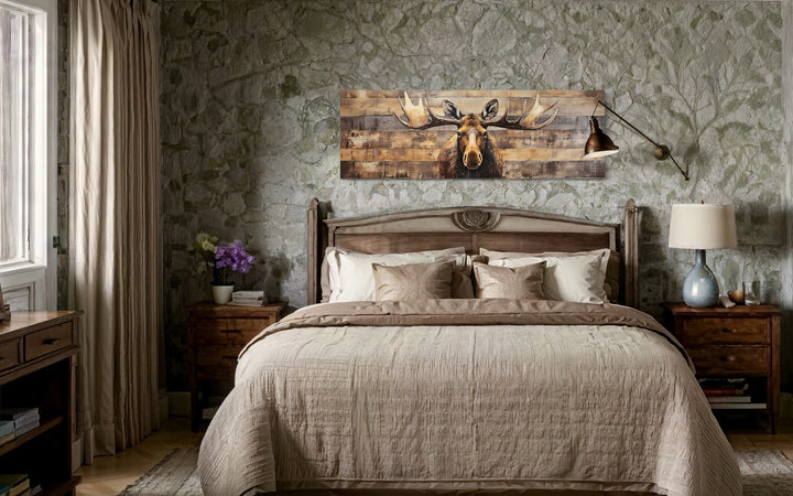 Moose painted on wood rustic horizontal framed canvas wall art hanging above a bed in a cabin.