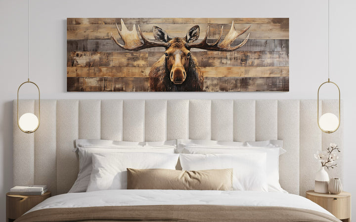 Rustic horizontal moose painting on wood-textured canvas hanging above a bed in a modern bedroom.