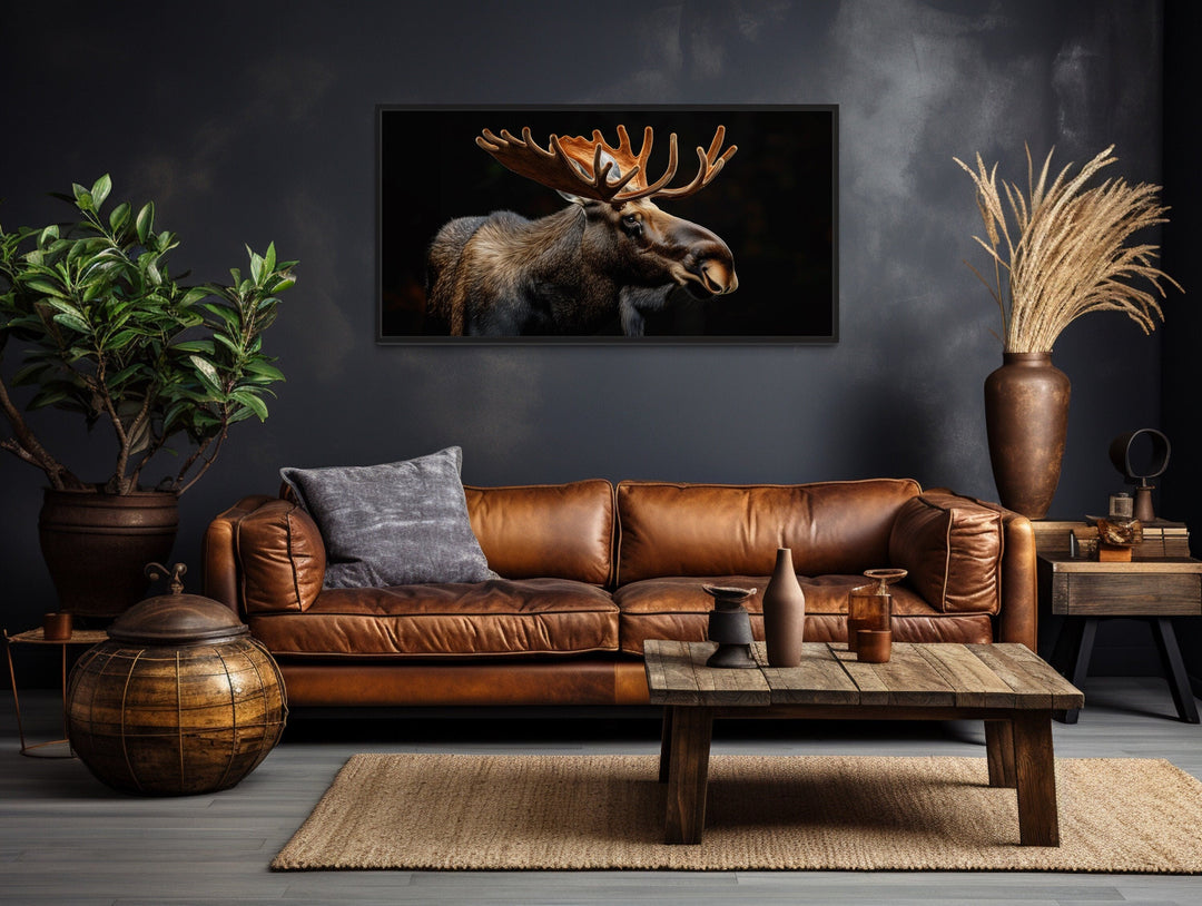 Extra large framed canvas of a moose with antlers against a black background in a rustic room.