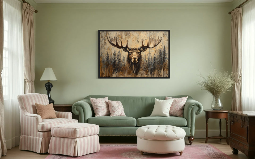Moose portrait on wood-look rustic framed canvas wall art hanging above a green sofa in a cabin.
