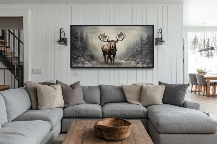 Moose in a foggy winter forest framed canvas wall art hanging above a gray sectional sofa.