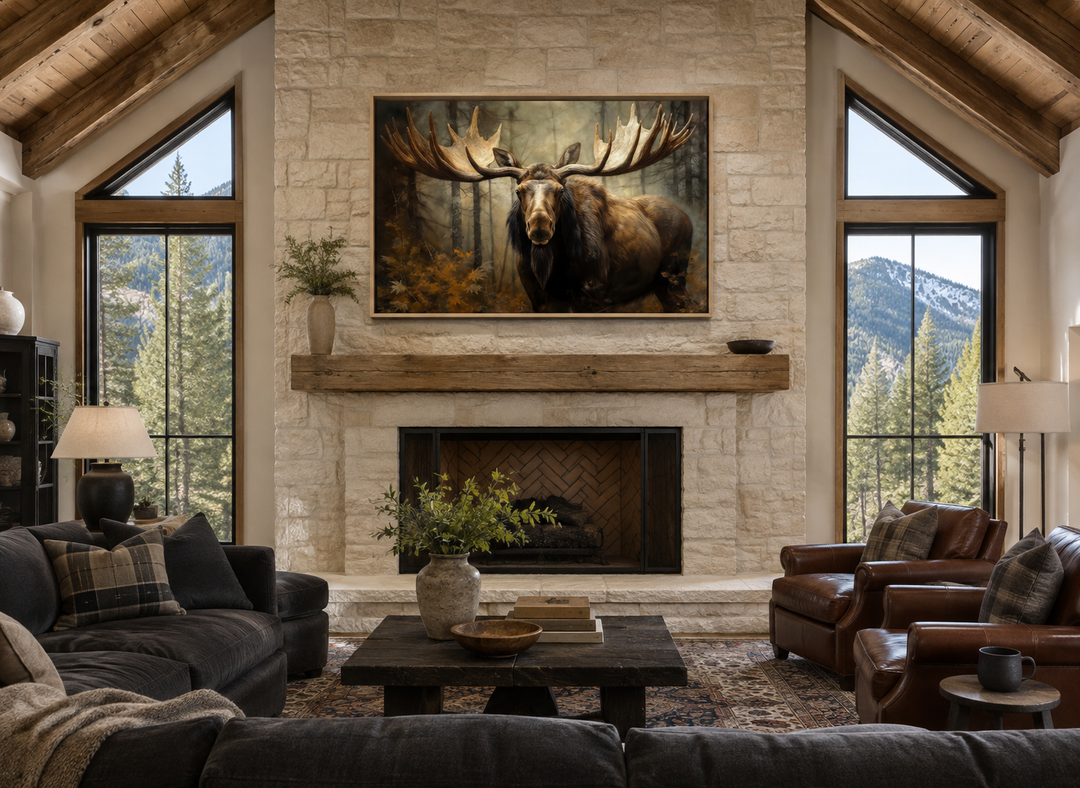 Moose with big antlers in the forest framed canvas wall art hanging above a stone fireplace.