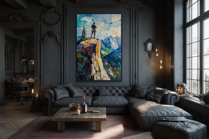 Vertical canvas print of a hiker on a cliff landscape displayed in a dark, modern living room.
