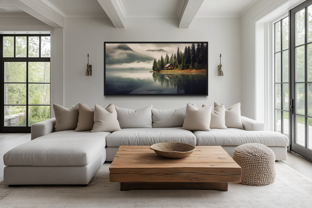 Large framed wall art of a mountain cabin on a lake in a modern living room.