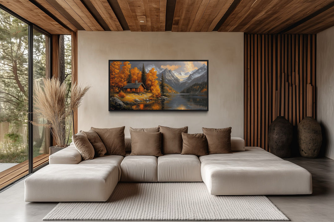 Mountain cabin wall art on a living room wall featuring a lake and warm autumn colors.