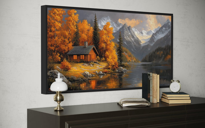 Mountain cabin wall art featuring a rustic cabin by a lake with warm autumn colors and mountains.