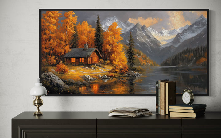 Framed canvas wall art of a rustic mountain cabin by a lake with vibrant autumn trees and mountains.