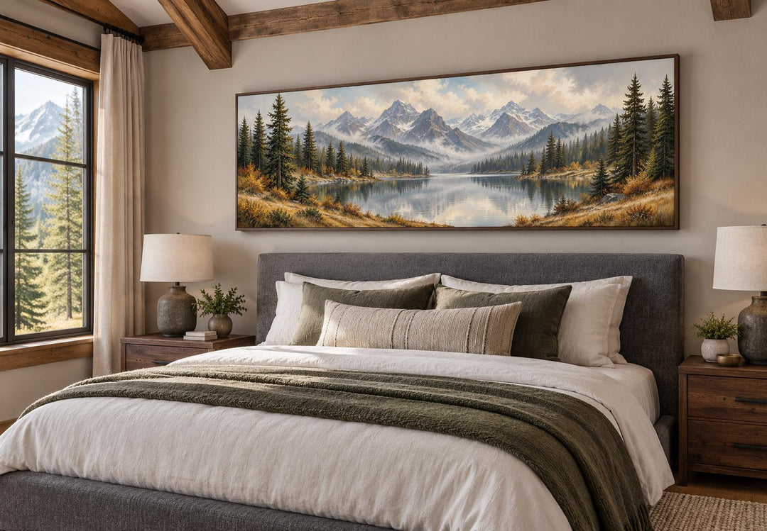 Long horizontal canvas wall art of a mountain lake and autumn forest above a bed in a rustic room.