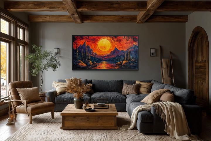 Mountain Lake Fiery Sunset canvas wall art displayed above a dark sofa in a rustic living room.