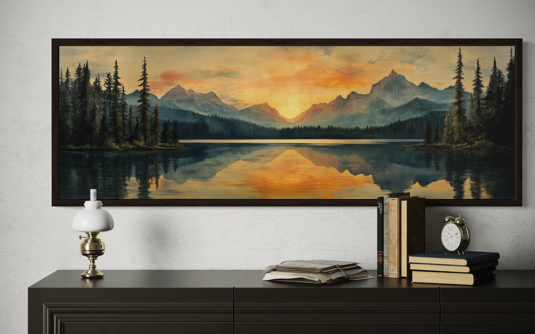 Panoramic wall art of a mountain lake sunset in a dark frame above a dark wood dresser.