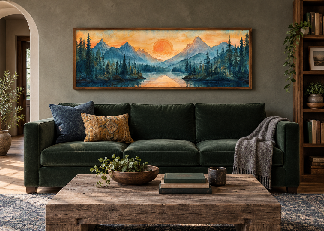Long horizontal watercolor wall art of a mountain lake sunset over a dark green velvet sofa.