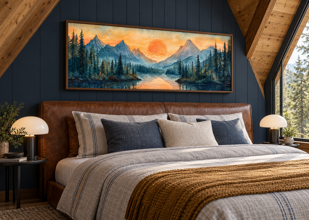 Long horizontal watercolor painting of a mountain lake sunset hanging above a leather bed.