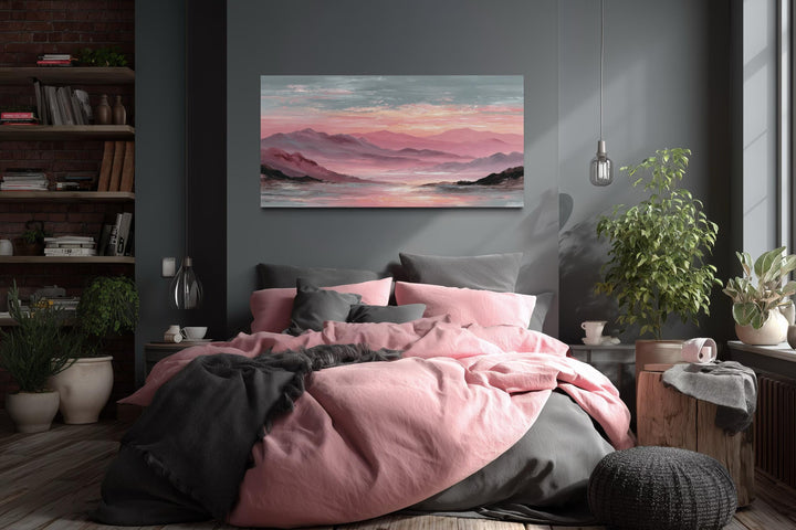 Mountain landscape canvas print with pink and grey tones hanging above a bed with matching bedding.