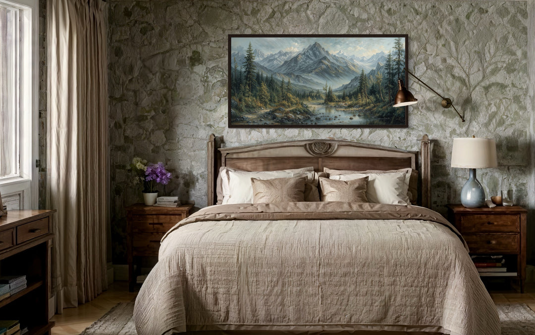 Mountain river landscape framed canvas art above a bed in a rustic room with stone walls.