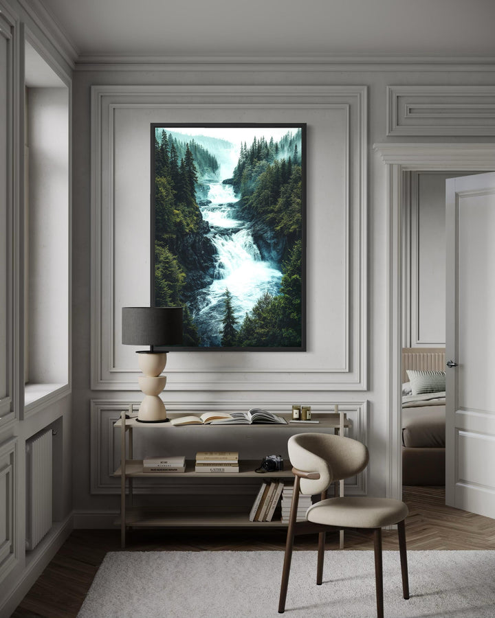 A vertical canvas print of a rushing mountain waterfall through a dense pine forest in a black frame.