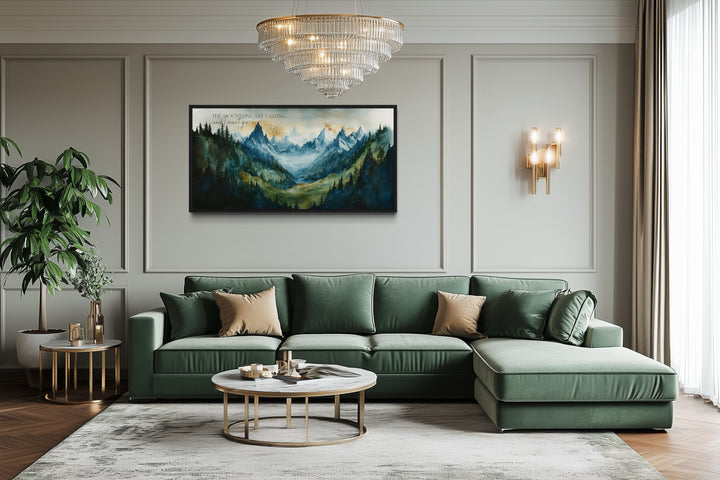Framed mountain landscape wall art with inspirational quote above a green sectional sofa.
