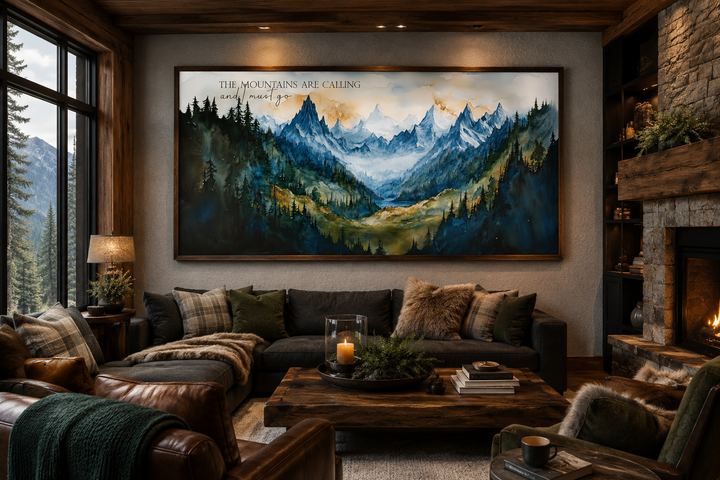 Framed watercolor mountain landscape wall art with quote above a sofa in a rustic cabin living room.