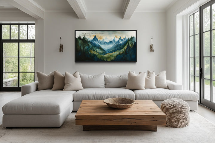 Framed mountain landscape wall art with inspirational quote above a modern sectional sofa.