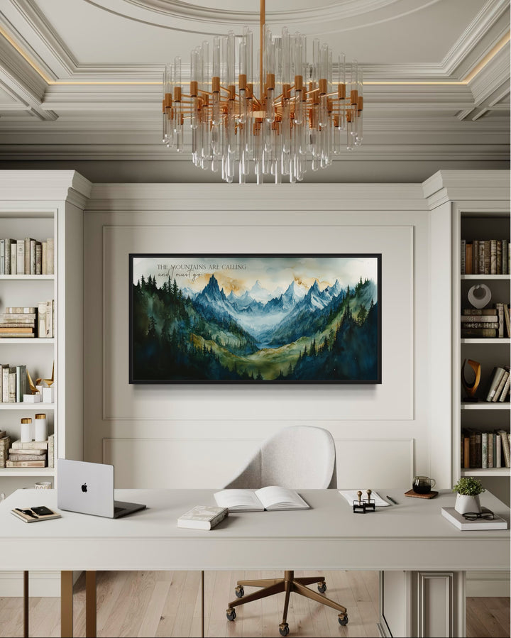 Framed mountain landscape wall art with inspirational quote above a desk in a modern office.
