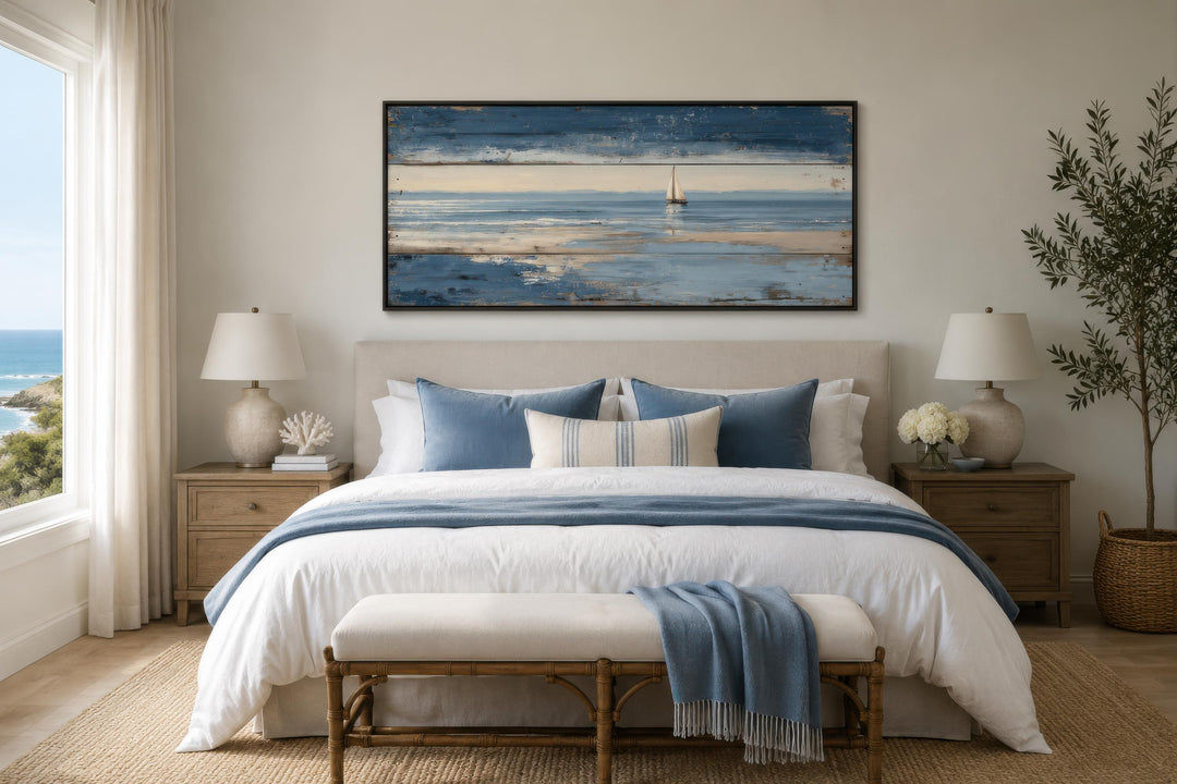 Nautical wall art featuring a lone sailboat canvas print with a distressed wood look above a bed.