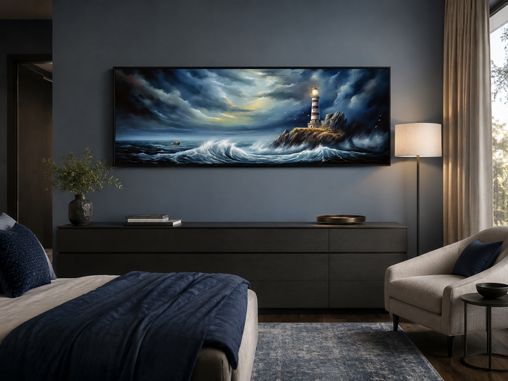 Dramatic long horizontal wall art of a lighthouse in a stormy ocean above a dark bedroom dresser.