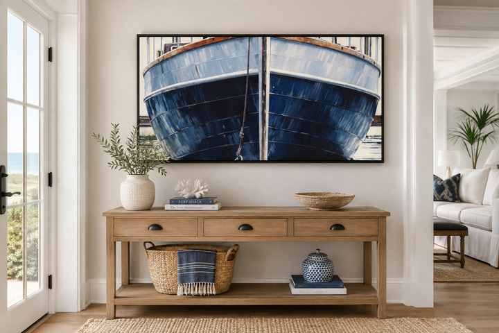 Navy blue rustic boat painting in a black frame above a wooden console table in a coastal entryway.