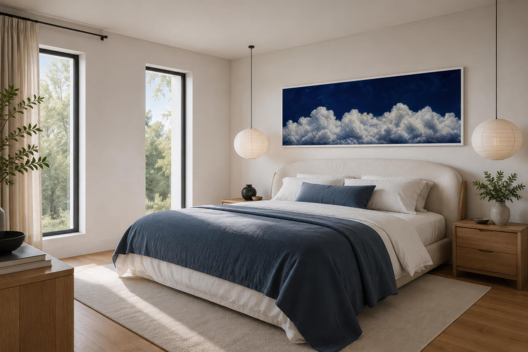 Navy blue cloud wall art, a long narrow canvas print, hanging above a bed in a modern bedroom.