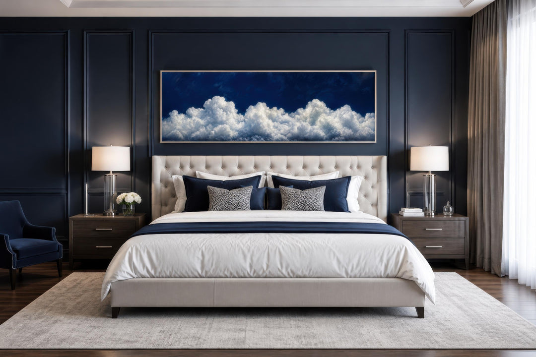 Long narrow canvas print of white clouds against a navy blue sky above a tufted headboard.