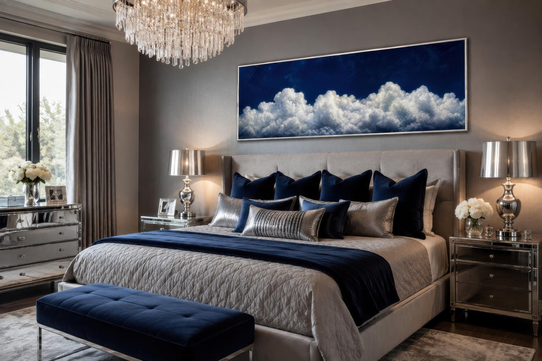 Long narrow canvas print of white clouds against a navy blue sky above a bed in a modern bedroom.