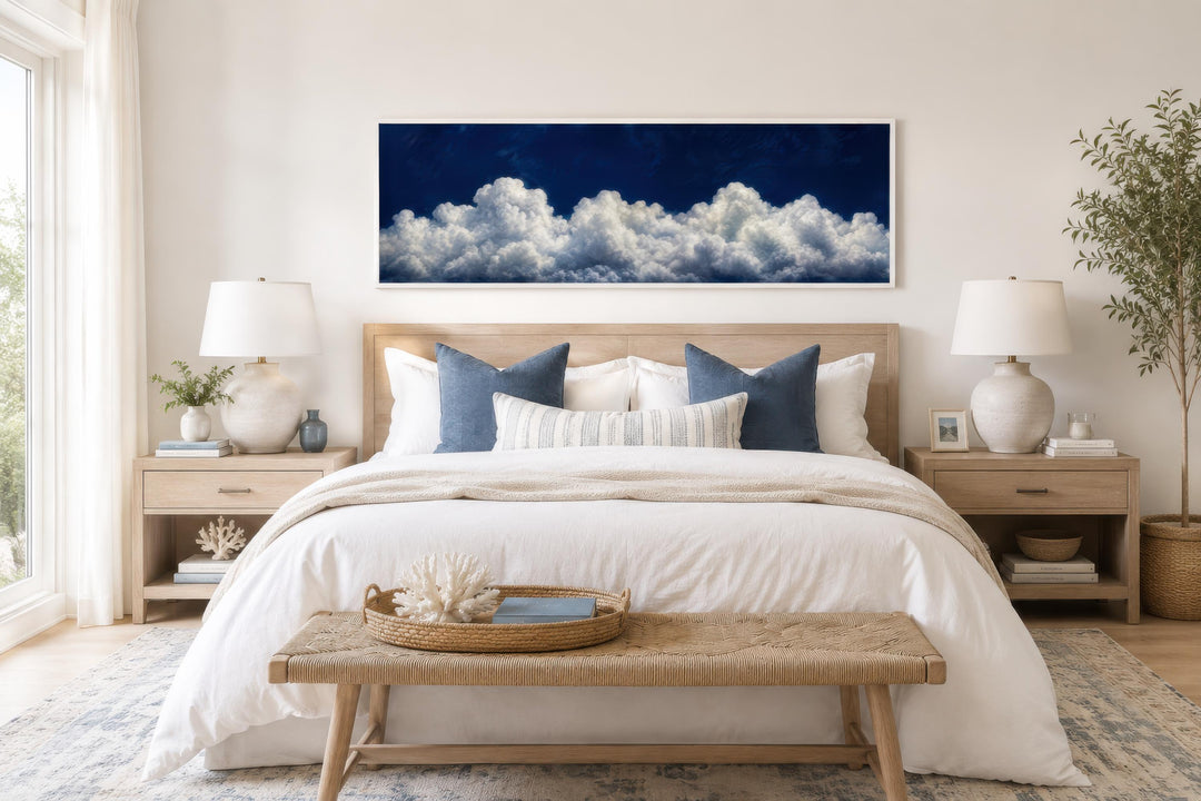 Long narrow canvas print of billowing white clouds against a deep navy blue sky above a bed.