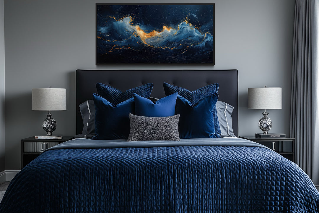 Abstract navy blue and gold ocean wave canvas wall art hanging above a bed with blue bedding.