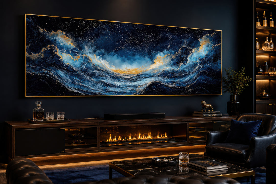 Large horizontal navy blue and gold ocean wave canvas wall art above a fireplace in a modern room.