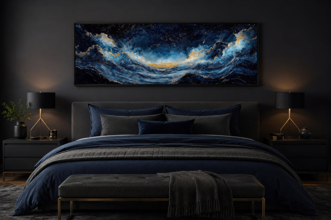 Navy blue and gold ocean wave horizontal canvas wall art hanging above a bed in a dark bedroom.