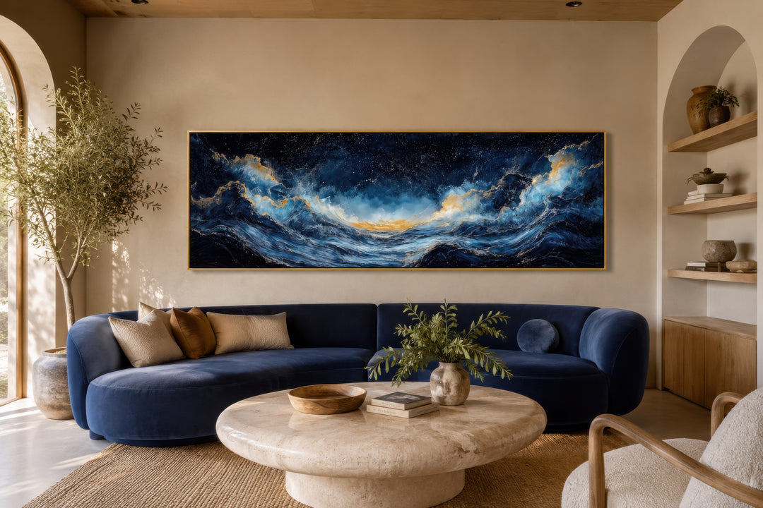 Navy blue and gold ocean wave horizontal canvas wall art hanging above a blue sofa in a living room.