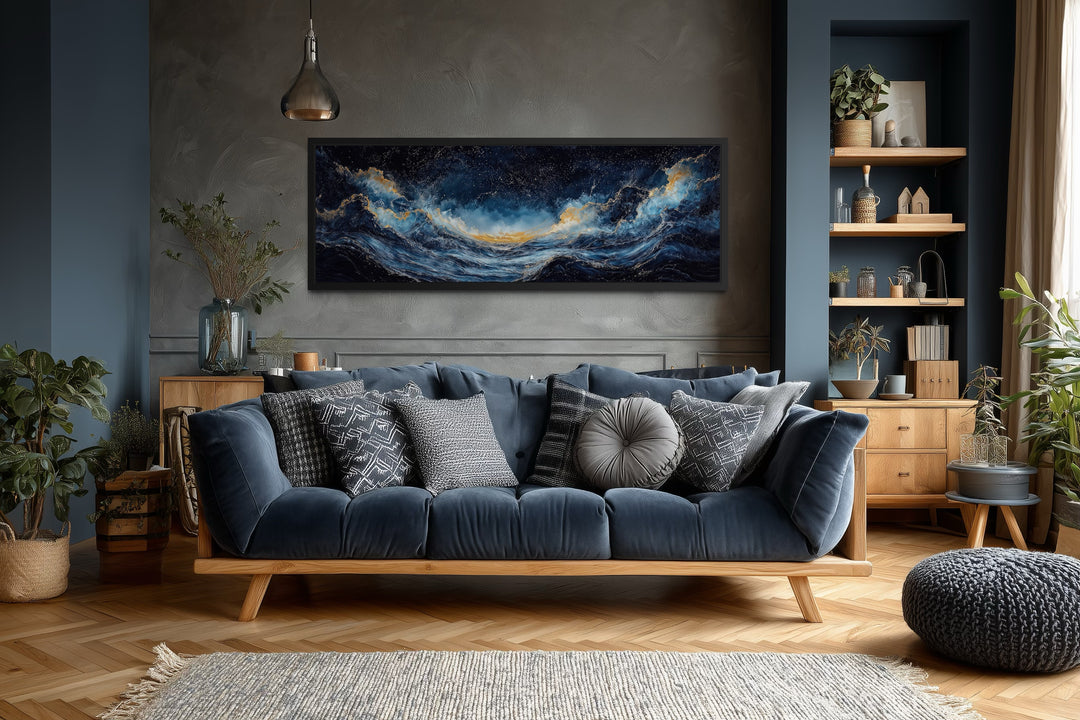 Navy blue and gold ocean wave horizontal canvas wall art hanging above a blue sofa in a living room.