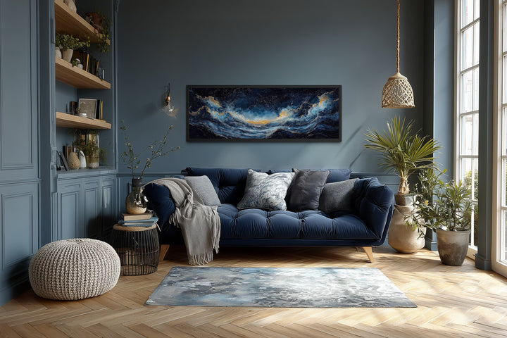 Navy blue and gold ocean wave horizontal canvas wall art hanging above a sofa in a living room.