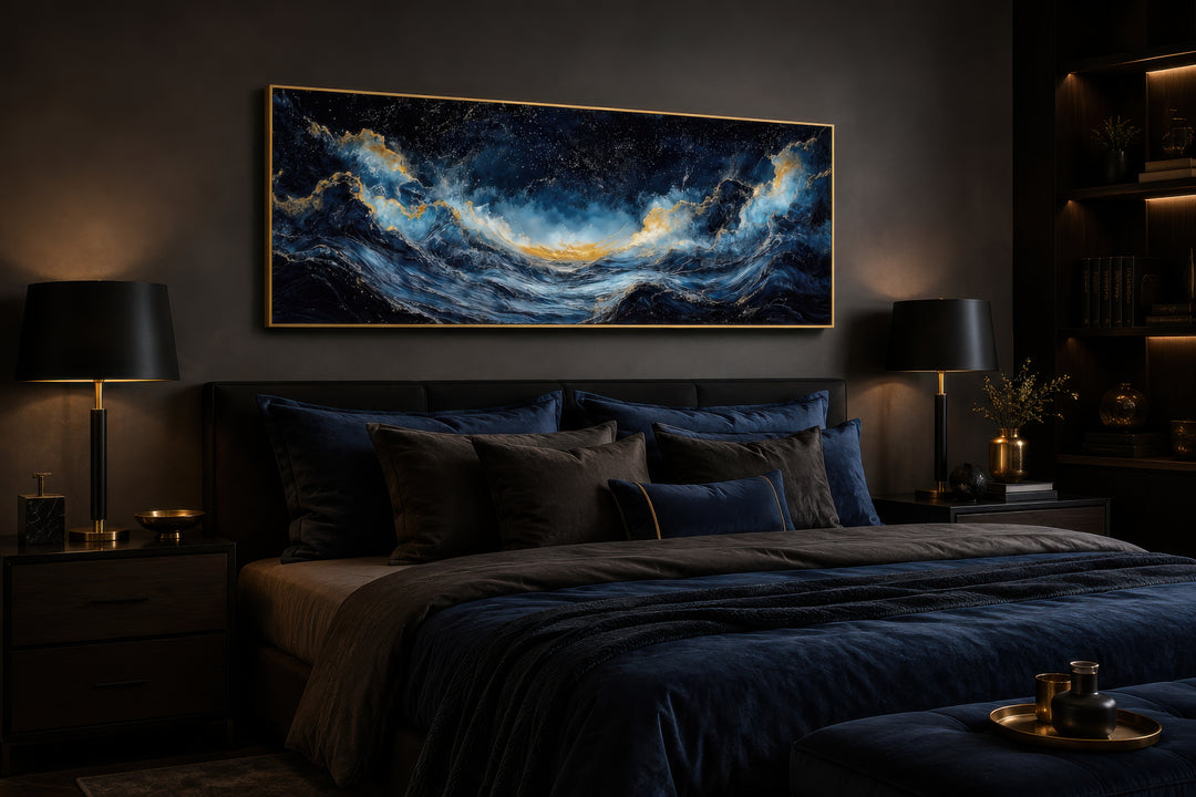 Navy blue and gold ocean wave horizontal canvas wall art hanging above a bed in a dark bedroom.