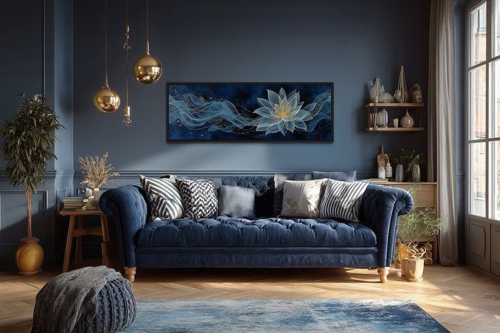 Navy blue and gold minimalist lotus flower canvas wall art above a tufted blue sofa.