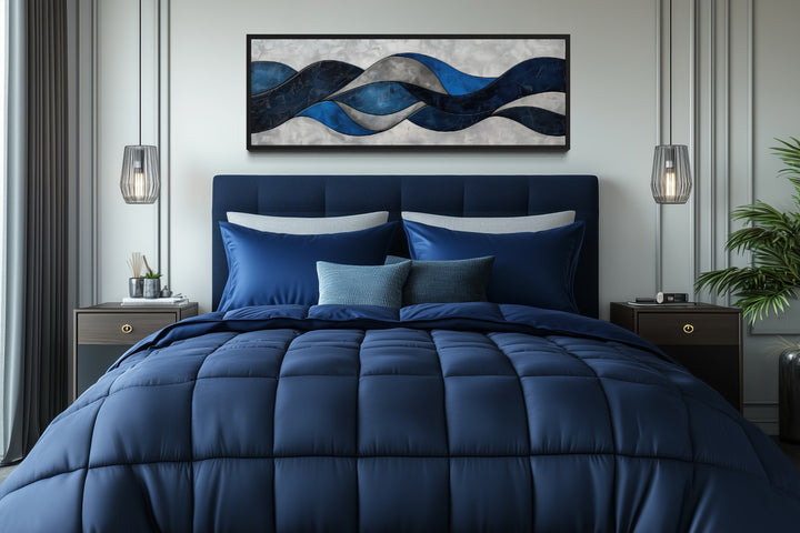 Navy blue and grey geometric abstract canvas wall art hanging above a bed in a modern bedroom.