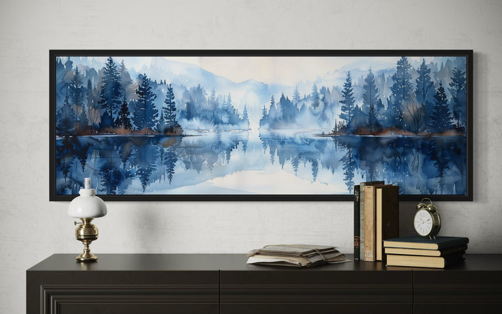 Navy blue lake watercolor landscape wall art in a black frame above a dark wood dresser.