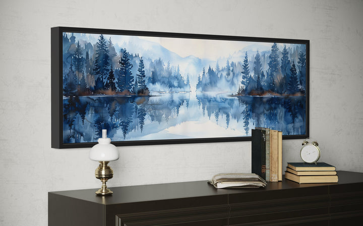 Navy blue lake landscape wall art in a black frame above a dark wood dresser with vintage decor.